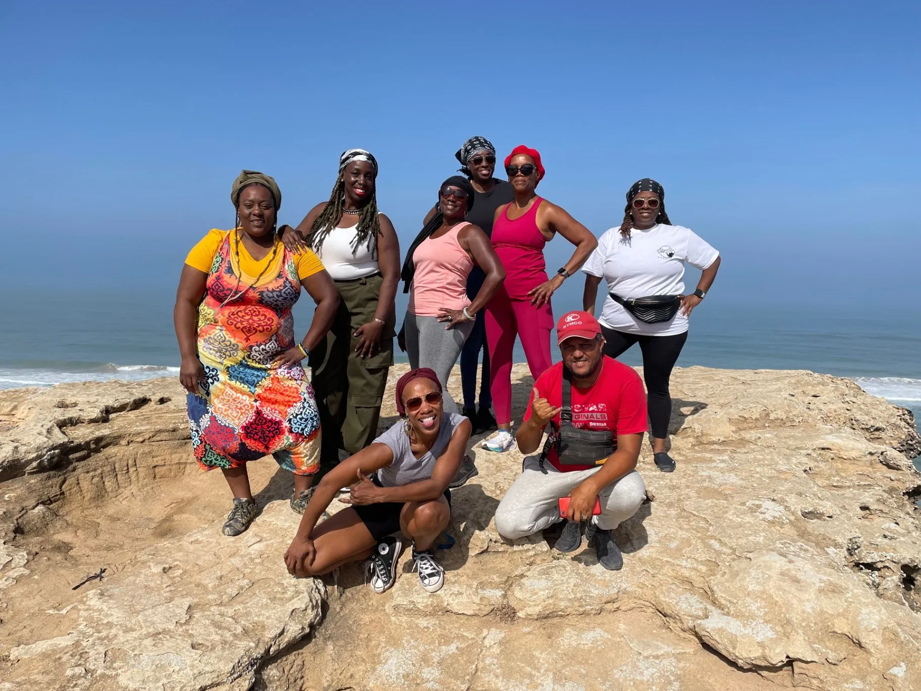 A joyful retreat group gathered together beside the ocean on a sunny coastal outing